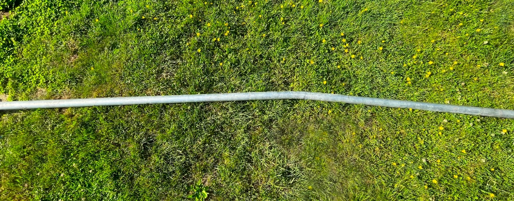 The bent pole lying in the grass after removal
